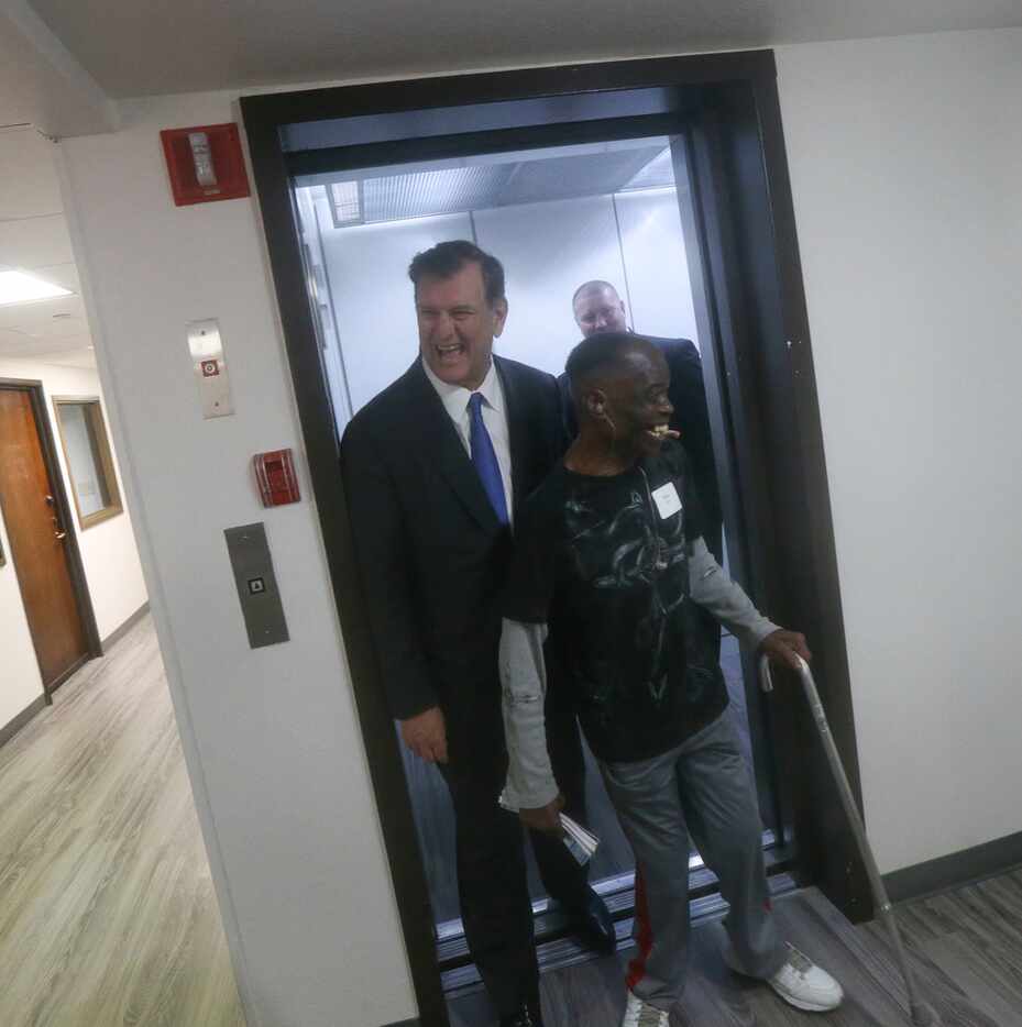 (From left) Dallas Mayor Mike Rawlings exits an elevator with resident Hilton Gray at the...