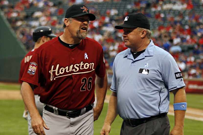 Houston Astros pitching coach Doug Brocail continues to argue as he is guided back to the...
