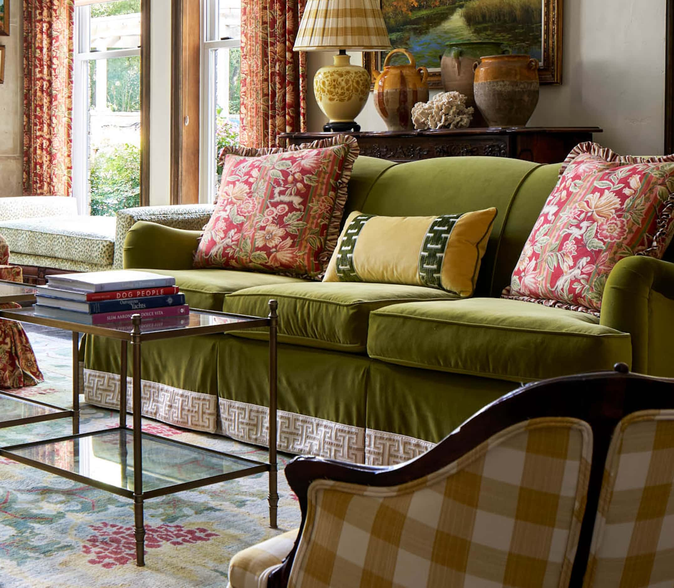 A green sofa with a Greek key trim sits on one side of a living room with a yellow-checked...