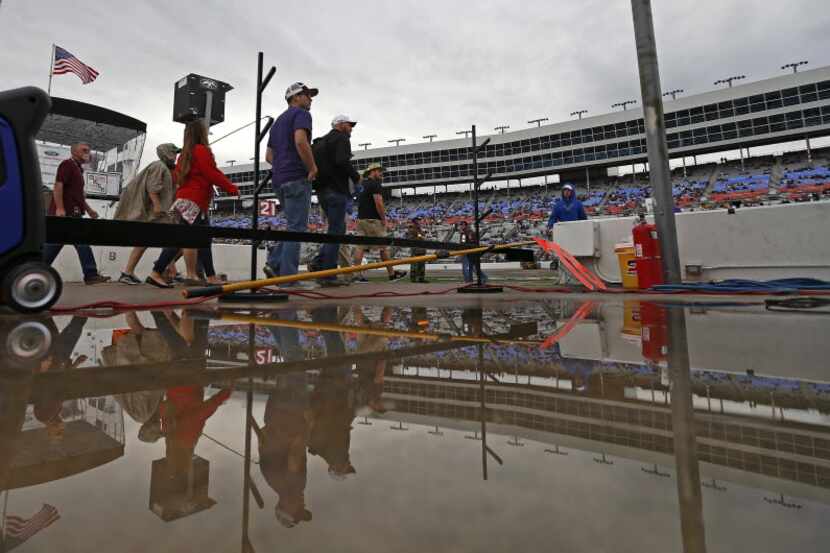 People are reflected in a puddle on the way to the infield during Duck Commander 500 at...