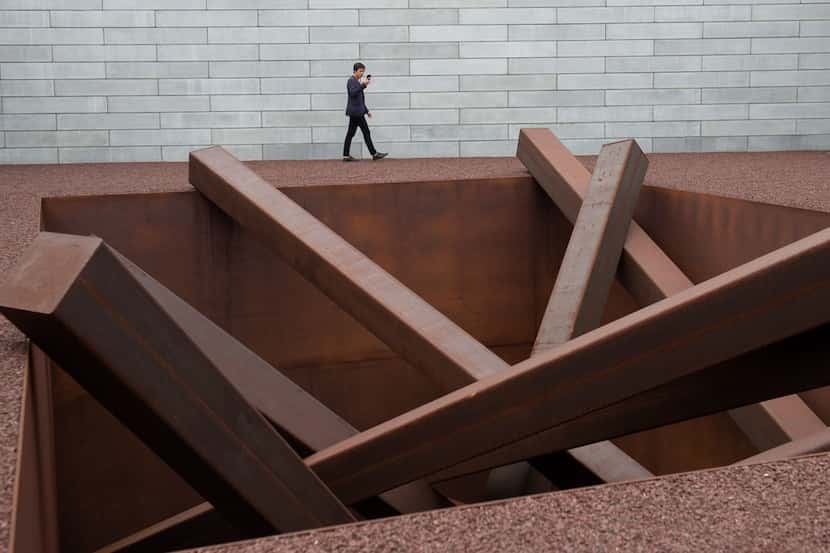 A man tours artist Michael Heizer's "Collapse," a sculpture of 15 steel beams arranged in a...