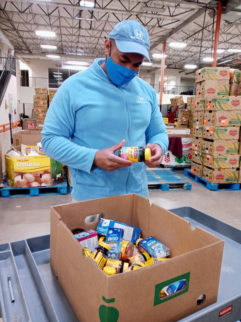 A member of the North Texas Helpful Honda Guys sorts through donations at a food bank.