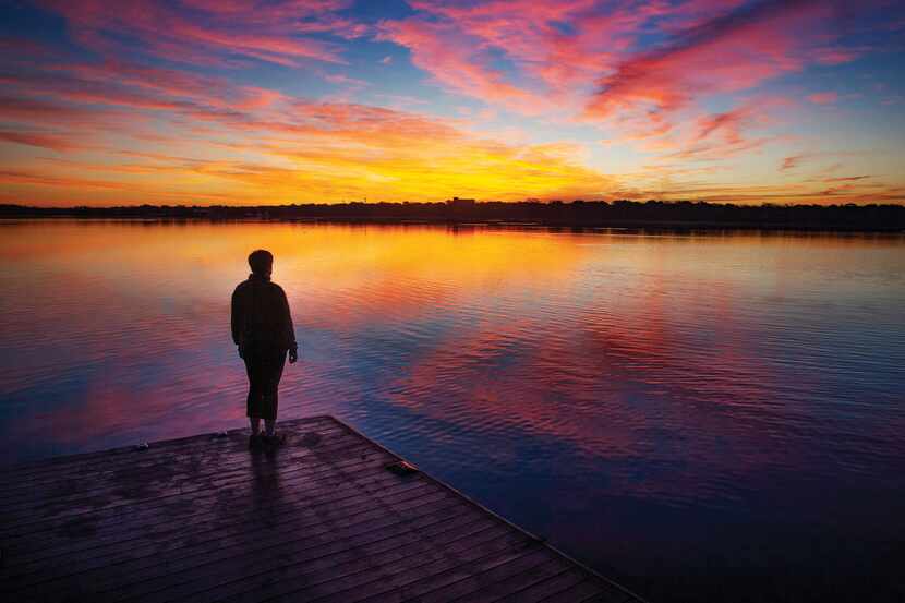 Amy Hofland, a survivor of thyroid cancer, stands before the sunrise over White Rock Lake in...