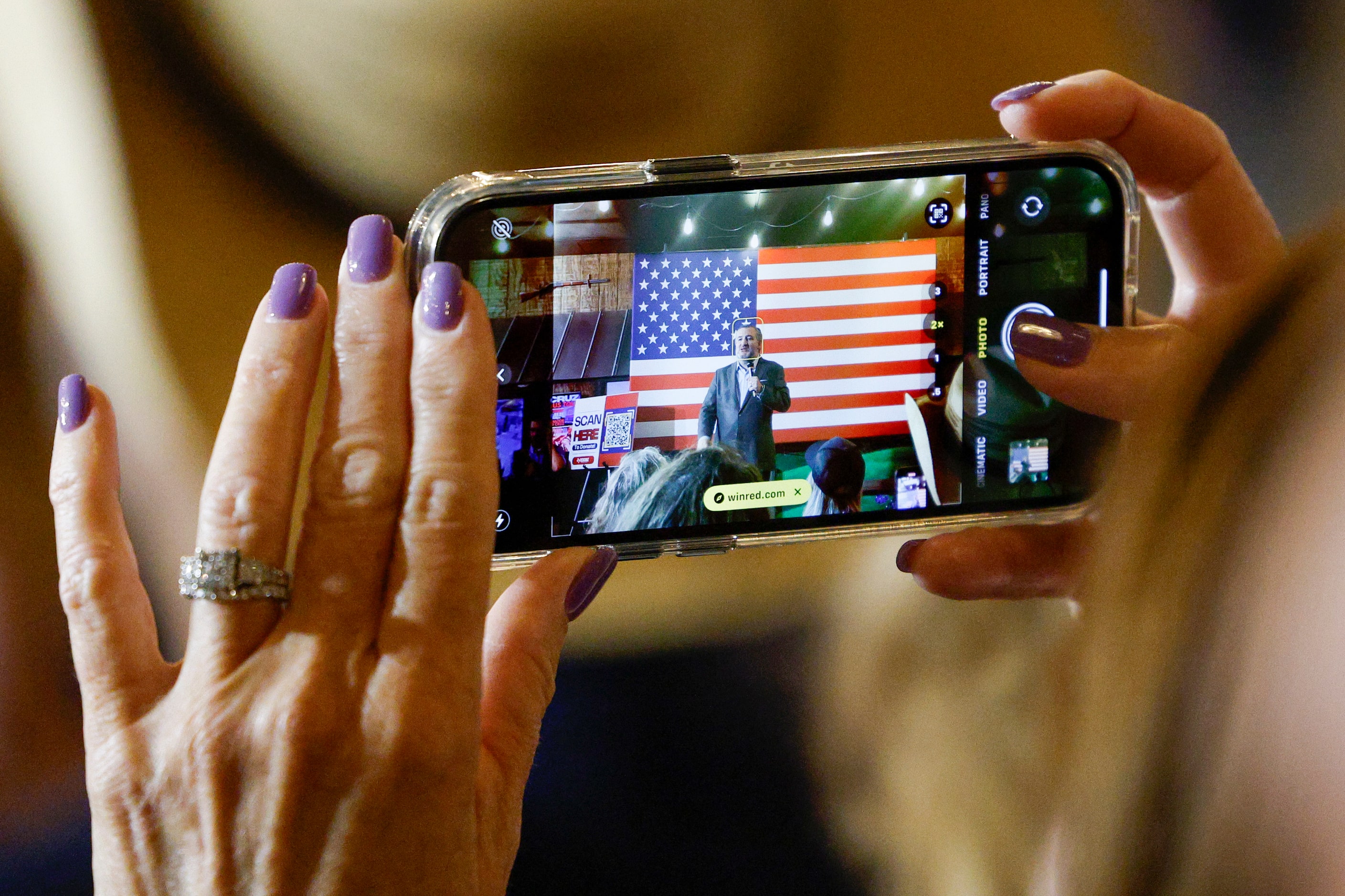 A woman takes a photo of Senator Ted Cruz (R-Texas) during a campaign rally at Outpost 36...