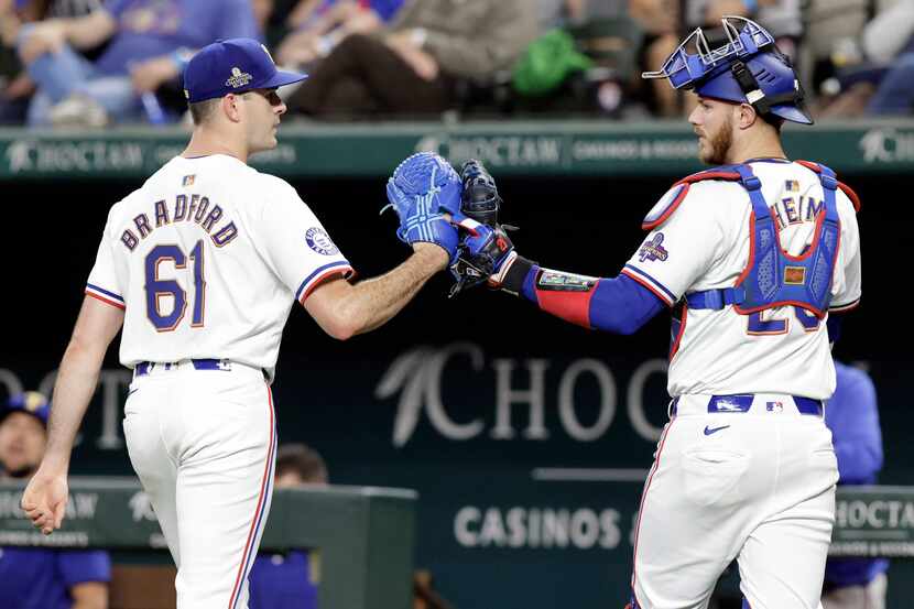 Texas Rangers pitcher Cody Bradford (61) bumps gloves with catcher Jonah Heim (28) after...