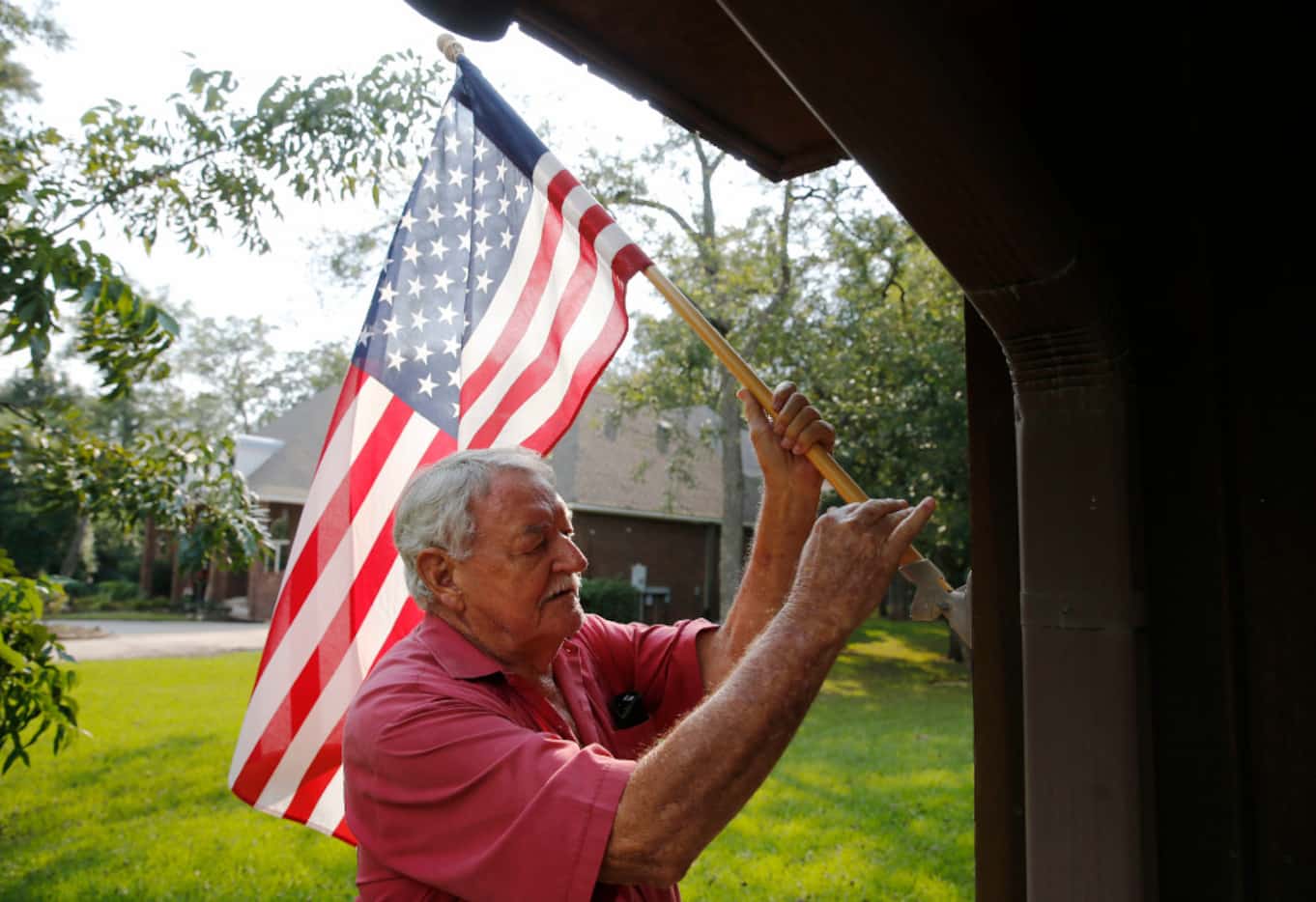 Jones Copeland of Richmond posts the American flag on the side of his house during cleanup...
