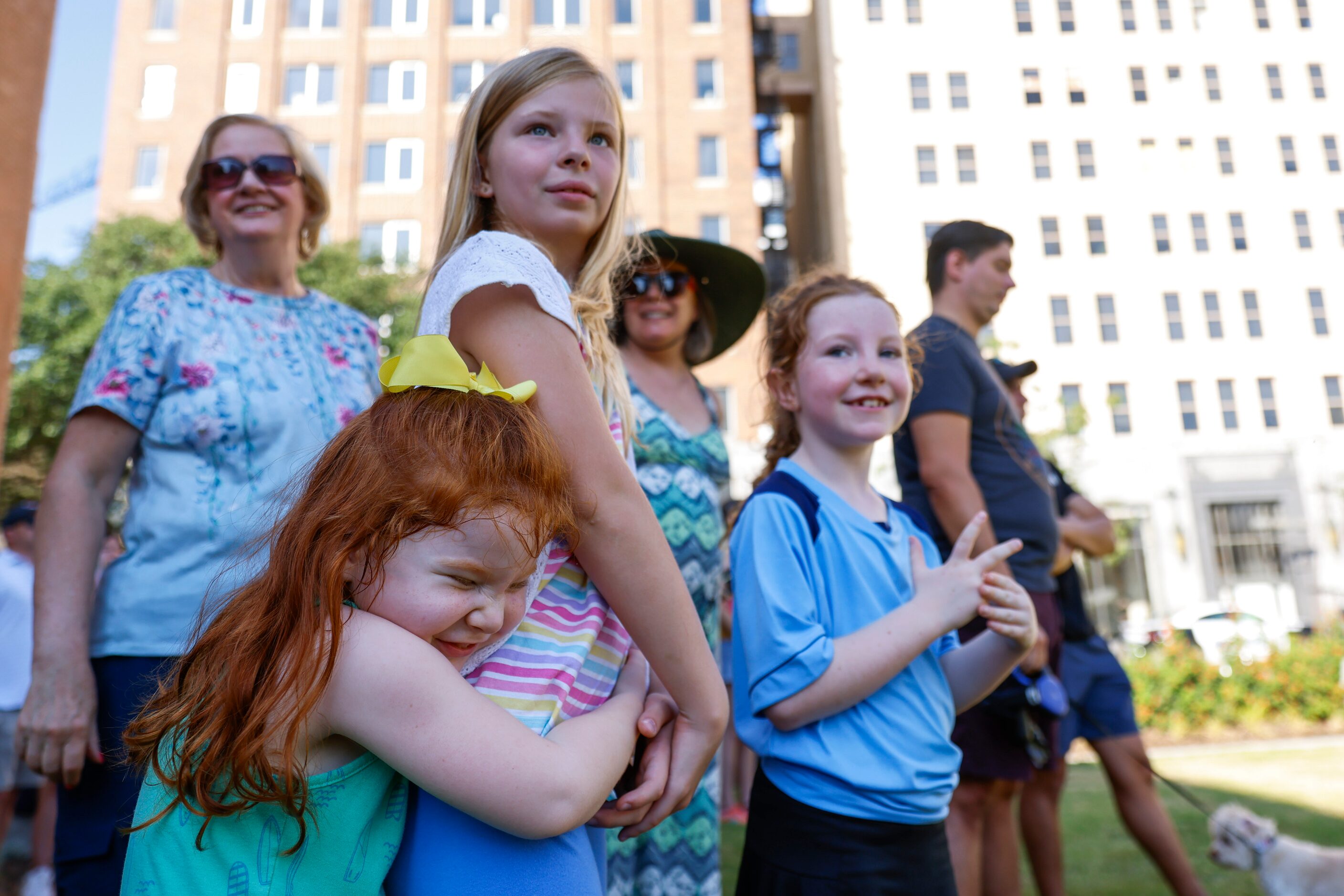 Madison Shipley, 4, (front), hugs as she plays with Adeline McKee, 8, (center), as her...