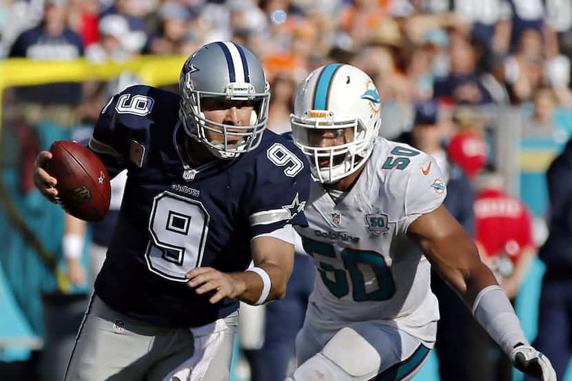 Dallas Cowboys quarterback Tony Romo (9) tries to escape Miami Dolphins defensive end...