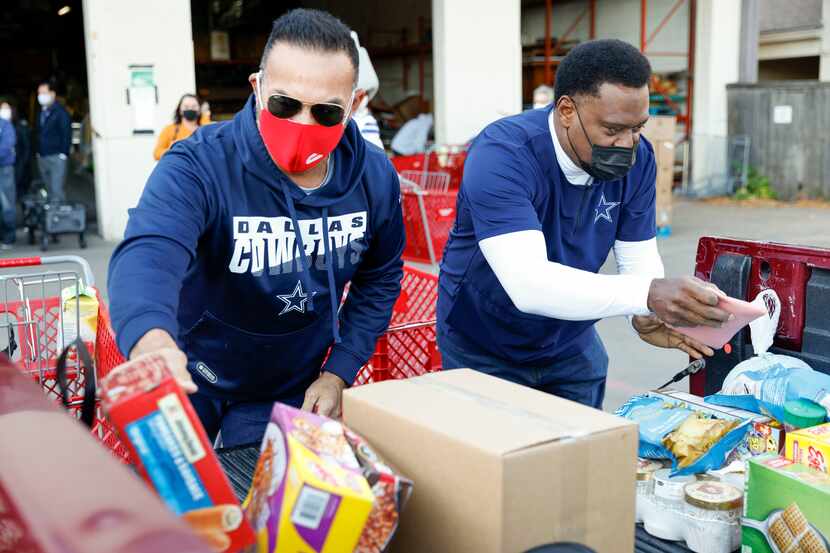 Former Dallas Cowboys players Tony Casillas (left) and George Teague loaded food into the...