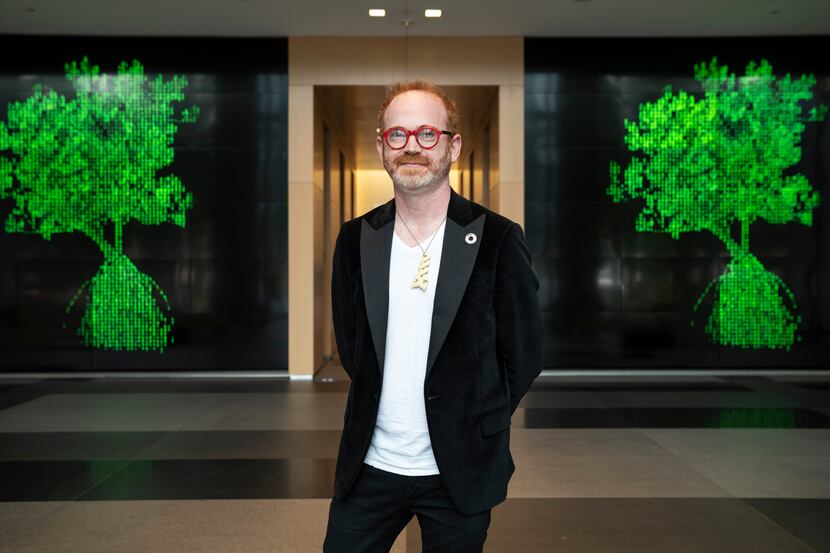 Jeremy McKane, 44, poses in front of two representations of his NFT creations inside the One...