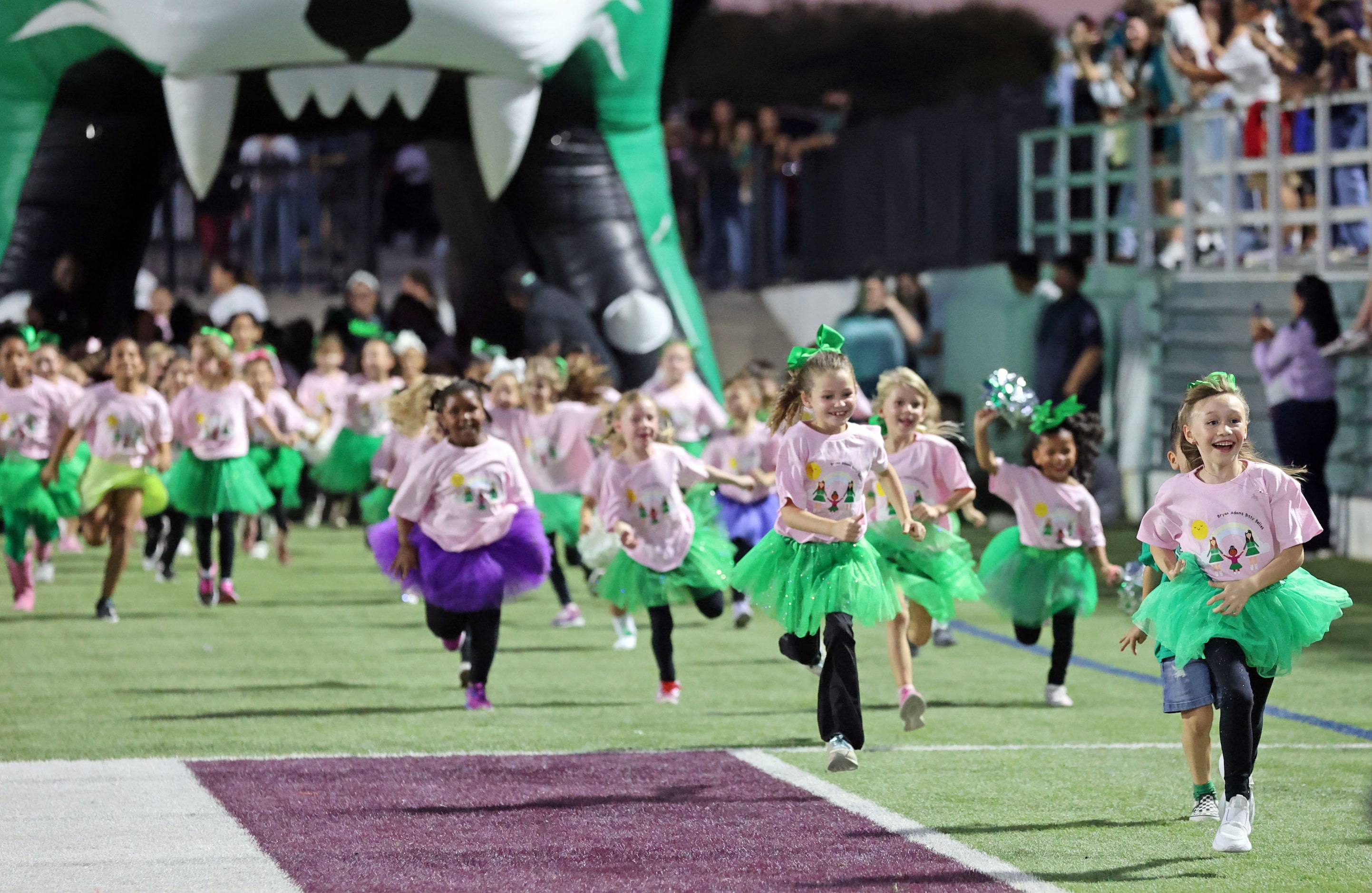 Young Bryan Adams High fans run onto the field before the start of a high school football...