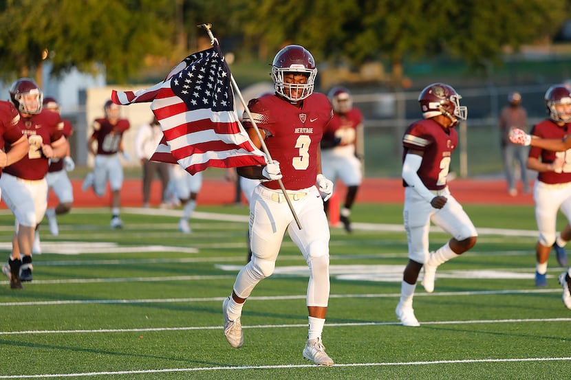Heritage High School wide receiver Jordan Gregory (3) carries the United States flag as the...