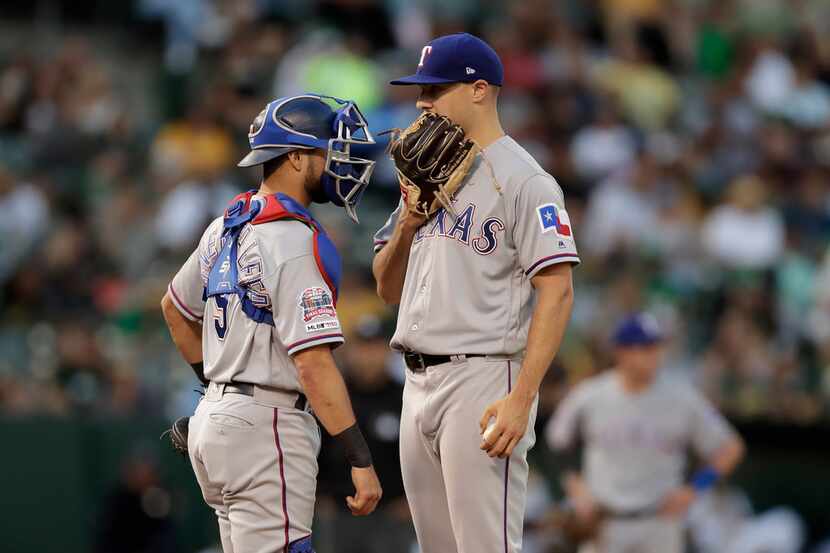 Texas Rangers pitcher Brock Burke, right, speaks with catcher Isiah Kiner-Falefa during the...