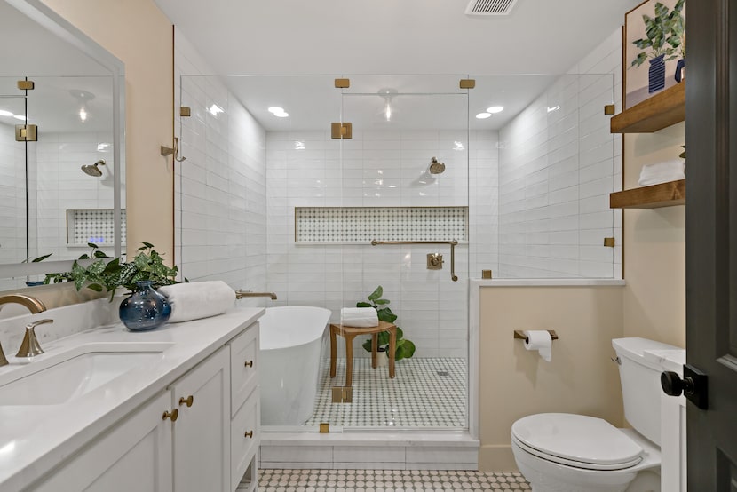 Bathroom with white cabinetry and countertops, wet area with white tile and freestanding tub...