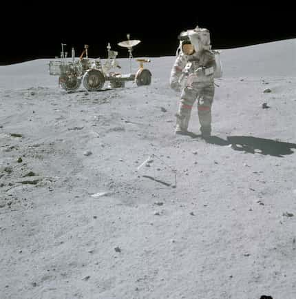 Astronaut John W. Young, Apollo 16 commander, with a sample bag in his left hand, moves...