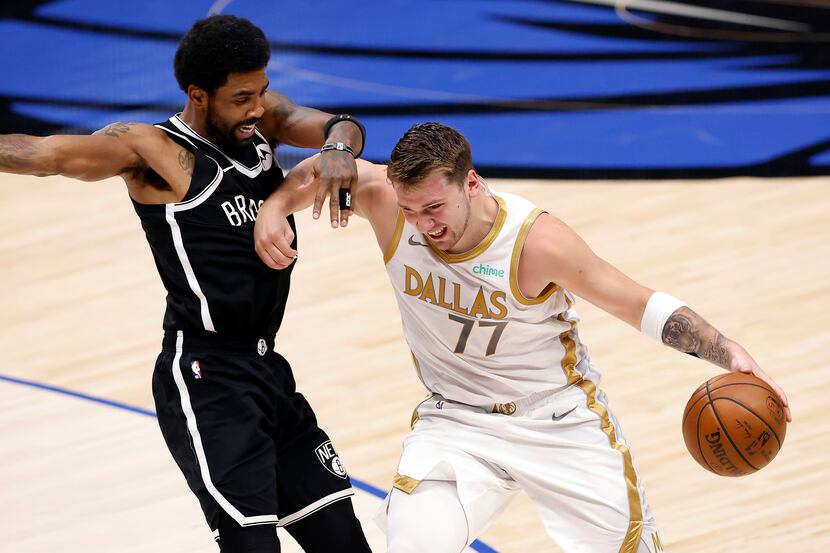 Dallas Mavericks guard Luka Doncic (77) forces his way past Brooklyn Nets guard Kyrie Irving...