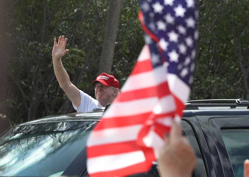 President Donald Trump waves from his vehicle after it stopped close to supporters near his...