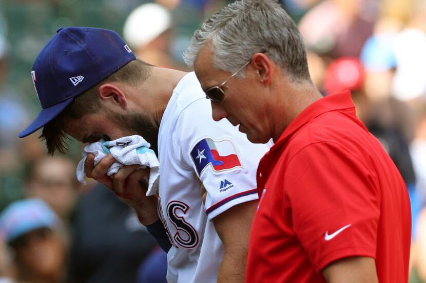 Texas Rangers third baseman Joey Gallo (13) is escorted off the field by trainer Kevin...