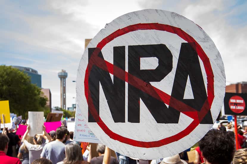 A demonstrator carries a sign in opposition to the National Rifle Association.