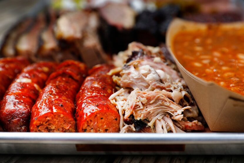 A tray of jalapeño and cheese sausage, pulled pork, beans, brisket and burnt ends is served...