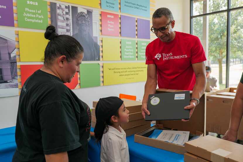 Kelem Butts, vice president of United Way of Metropolitan Dallas, shows a laptop to a family...