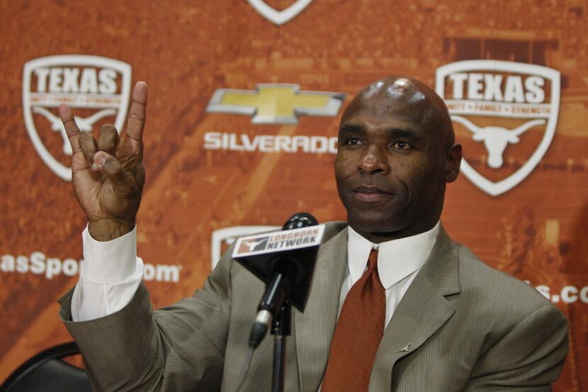 Charlie Strong flashes the "Hook 'Em Horns" sign after being introduced during a press...