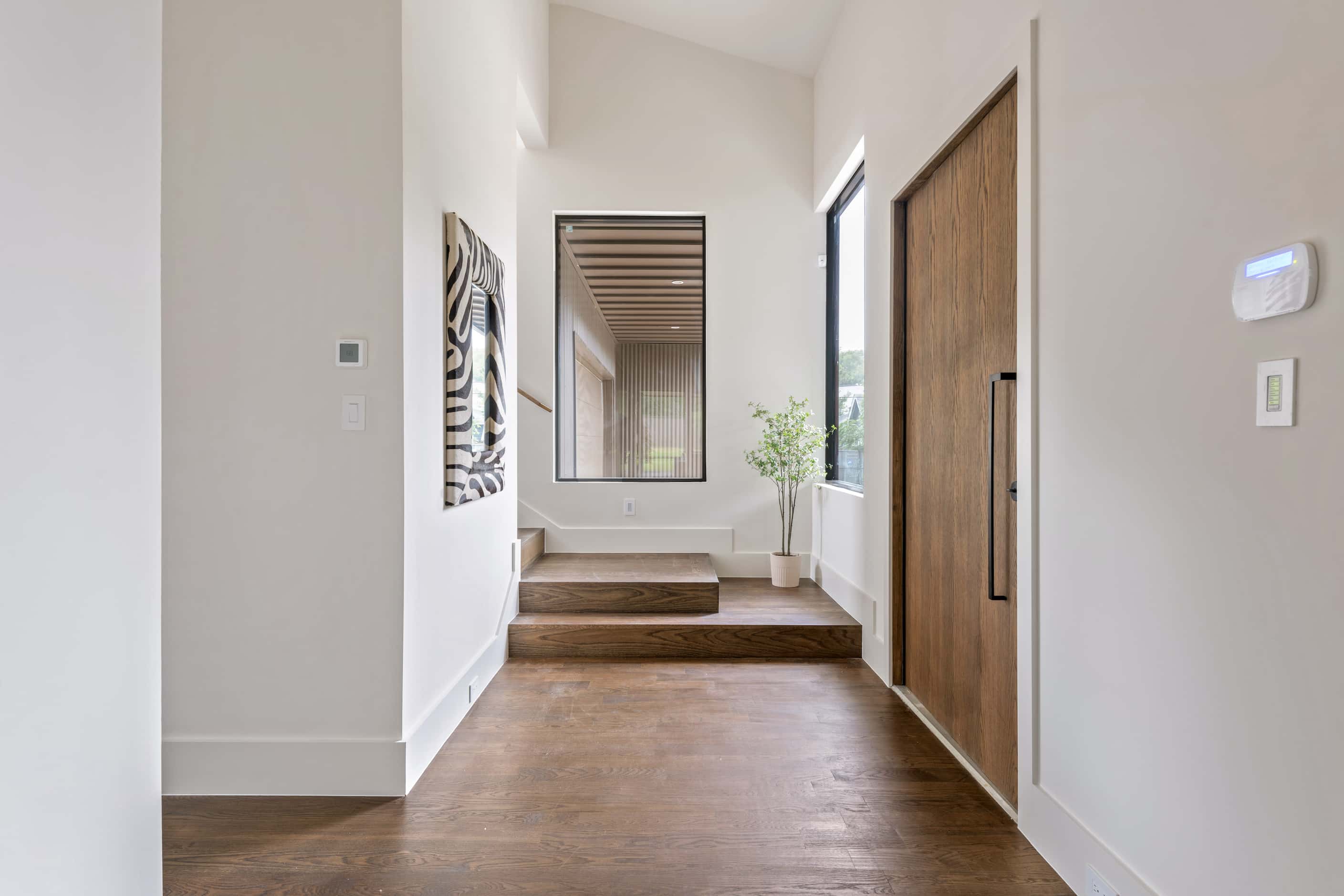 Stairway near the entry in a contemporary home, white walls, wood floors, wooden front door,...