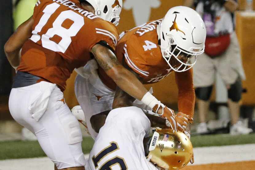 Texas safeties Kevin Vaccaro (18) and DeShon Elliott (4) apply a hard hit to Notre Dame wide...