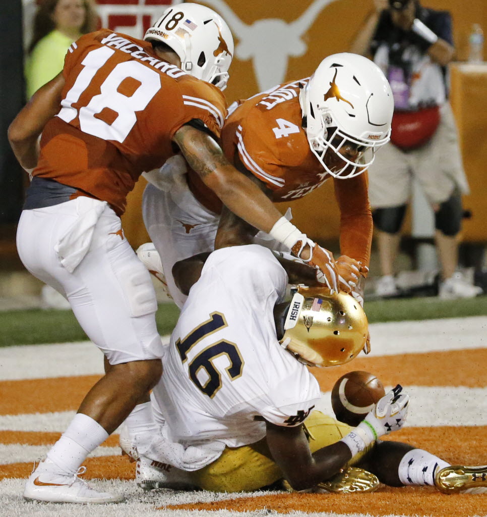 Texas safeties Kevin Vaccaro (18) and DeShon Elliott (4) apply a hard hit to Notre Dame wide...
