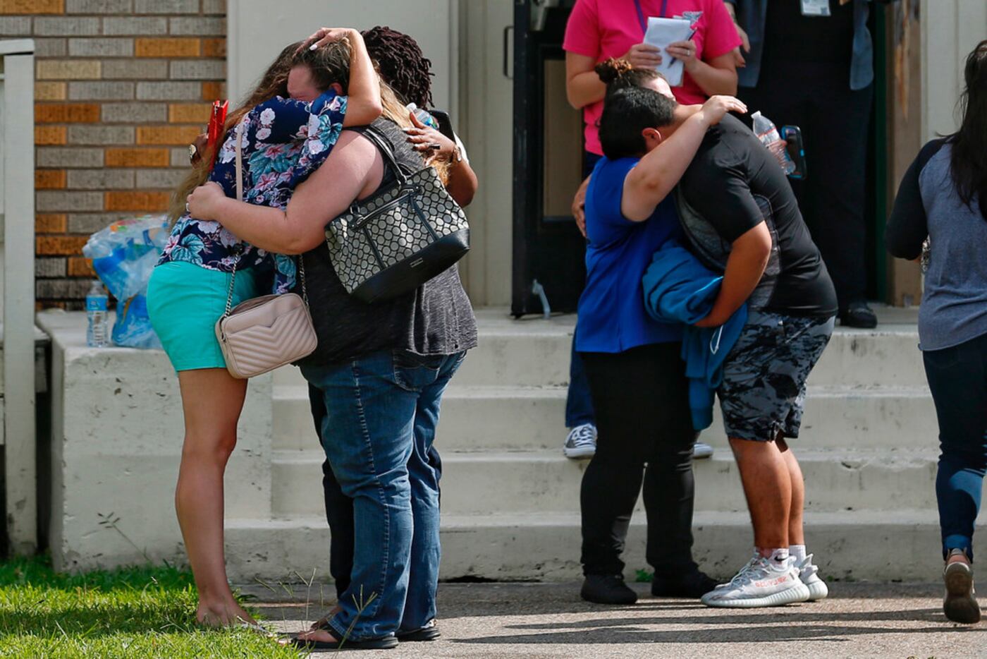 People embrace outside the Alamo Gym where students and parents wait to reunite following a...