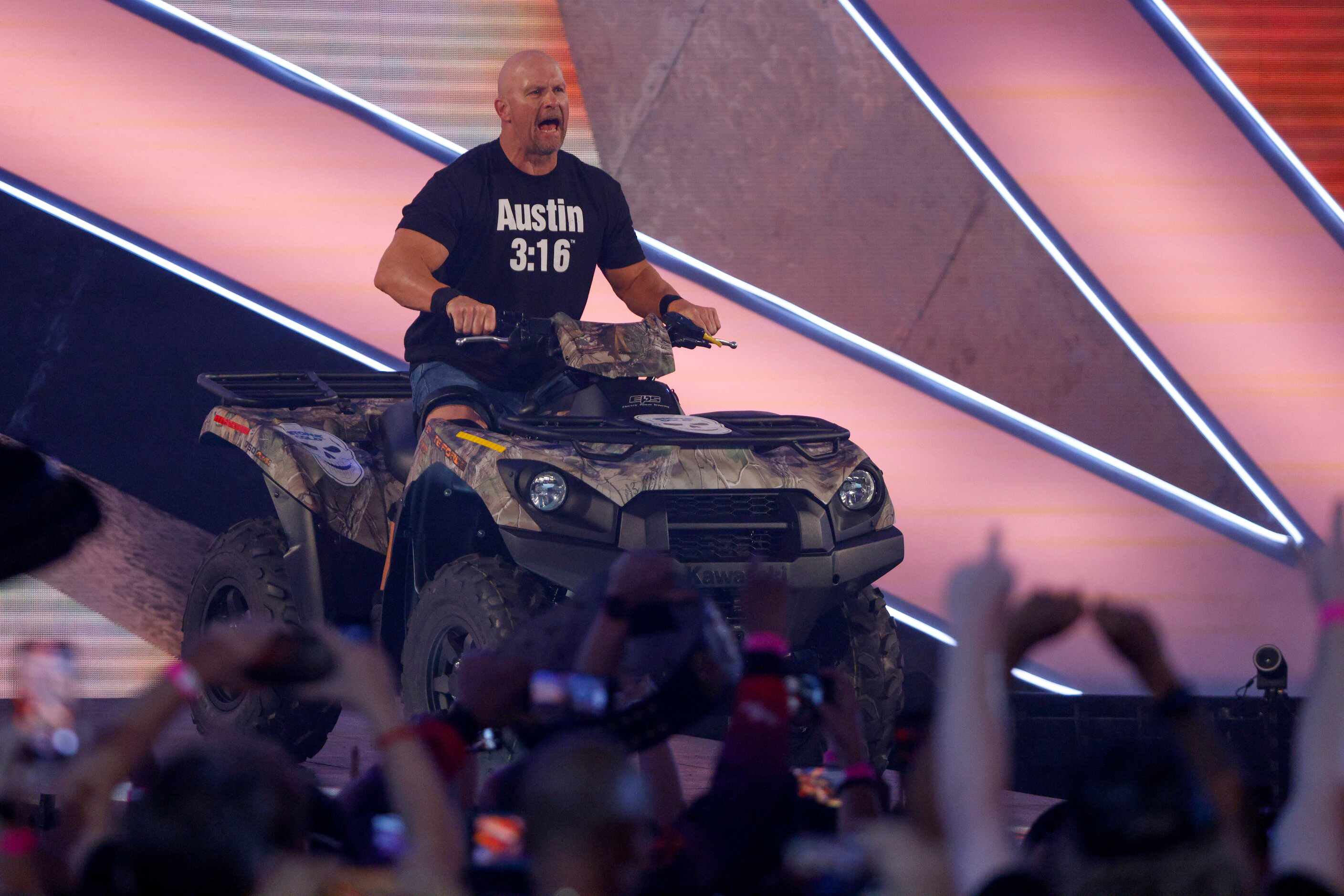 “Stone Cold” Steve Austin drives an ATV down the ramp to the ring before a match against...