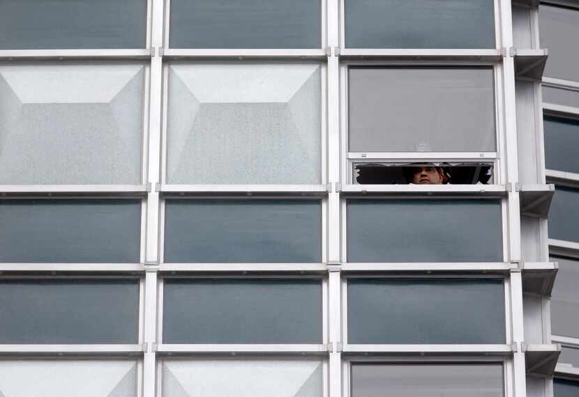 A Dallas Fire-Rescue captain is seen through a broken window on the 16th floor of the...