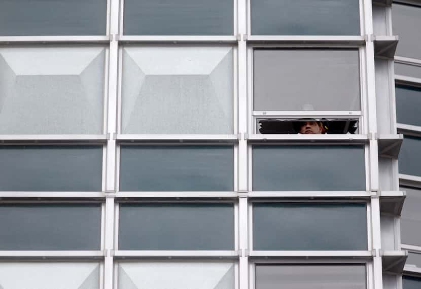 A Dallas Fire-Rescue captain is seen through a broken window on the 16th floor of the...