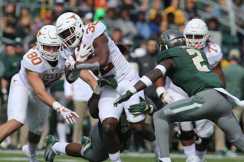Texas running back Daniel Young (32) slips past Baylor safety Taion Sells, right, for a...