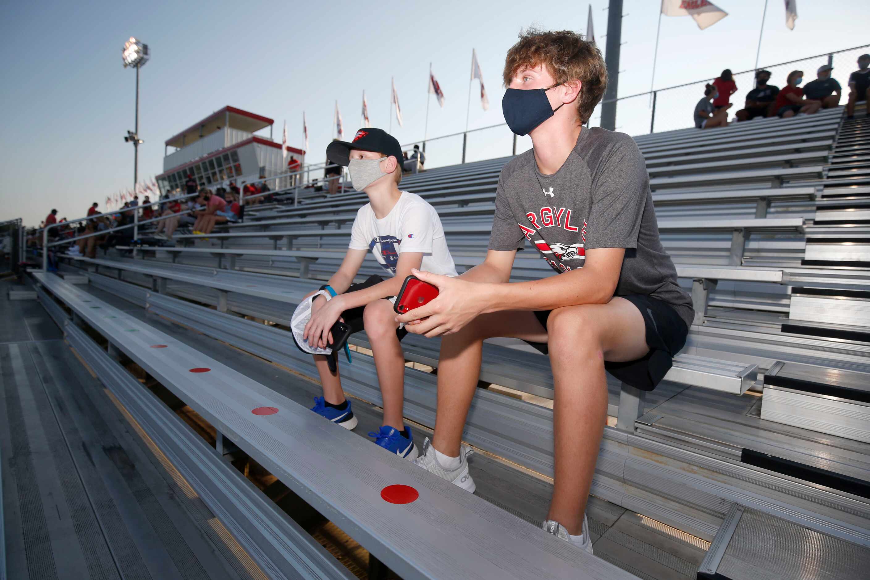 Jackson Weeks, left, and his brother Jadon Weeks sit in seats marked by green dots, near...