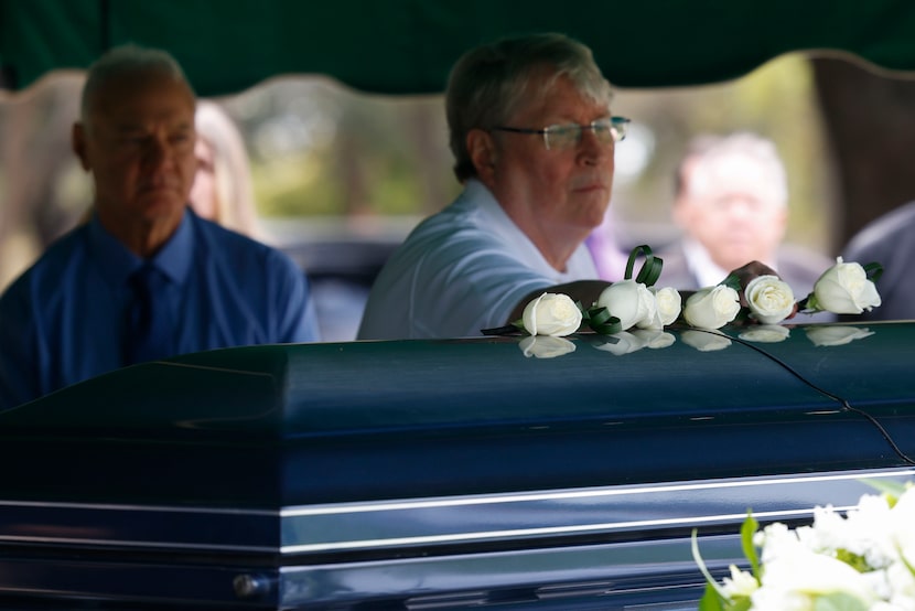 Gary Cox places a flower on his best friend’s casket during the burial service of Paul...