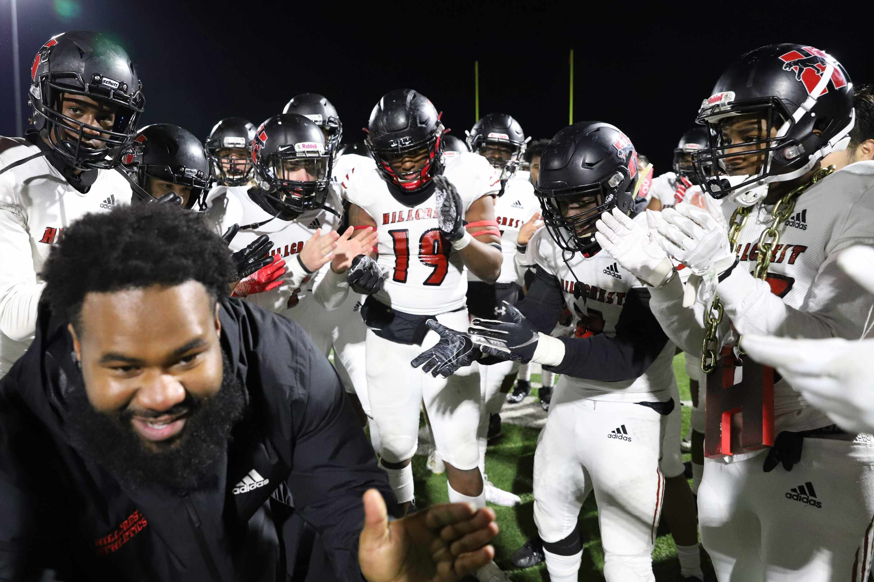Hillcrest outside linebackers coach Antonio Dudley leads the team in a chant after a win...