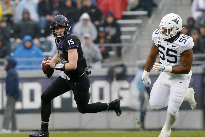 FILE - TCU quarterback Max Duggan (15) runs away form West Virginia defensive lineman Dante...