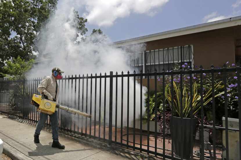 A Miami-Dade County mosquito control worker sprays around a home in the Wynwood area of...