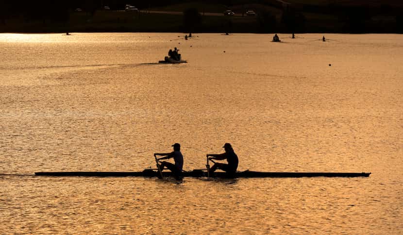 Members of the Dallas Rowing Club and Juniors program glide across Bachman Lake as they...