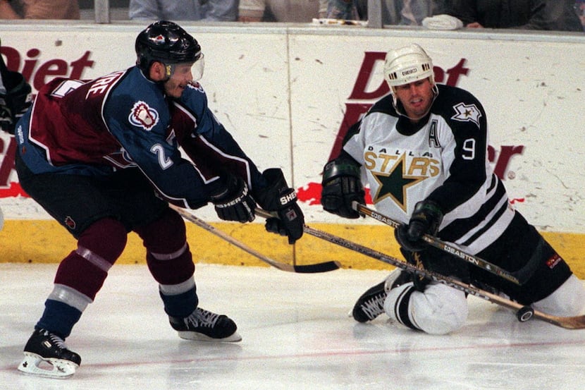 Mike Modano, #9, slides to try and make a pass out to a teammate, with Sylvain Lefebvre...