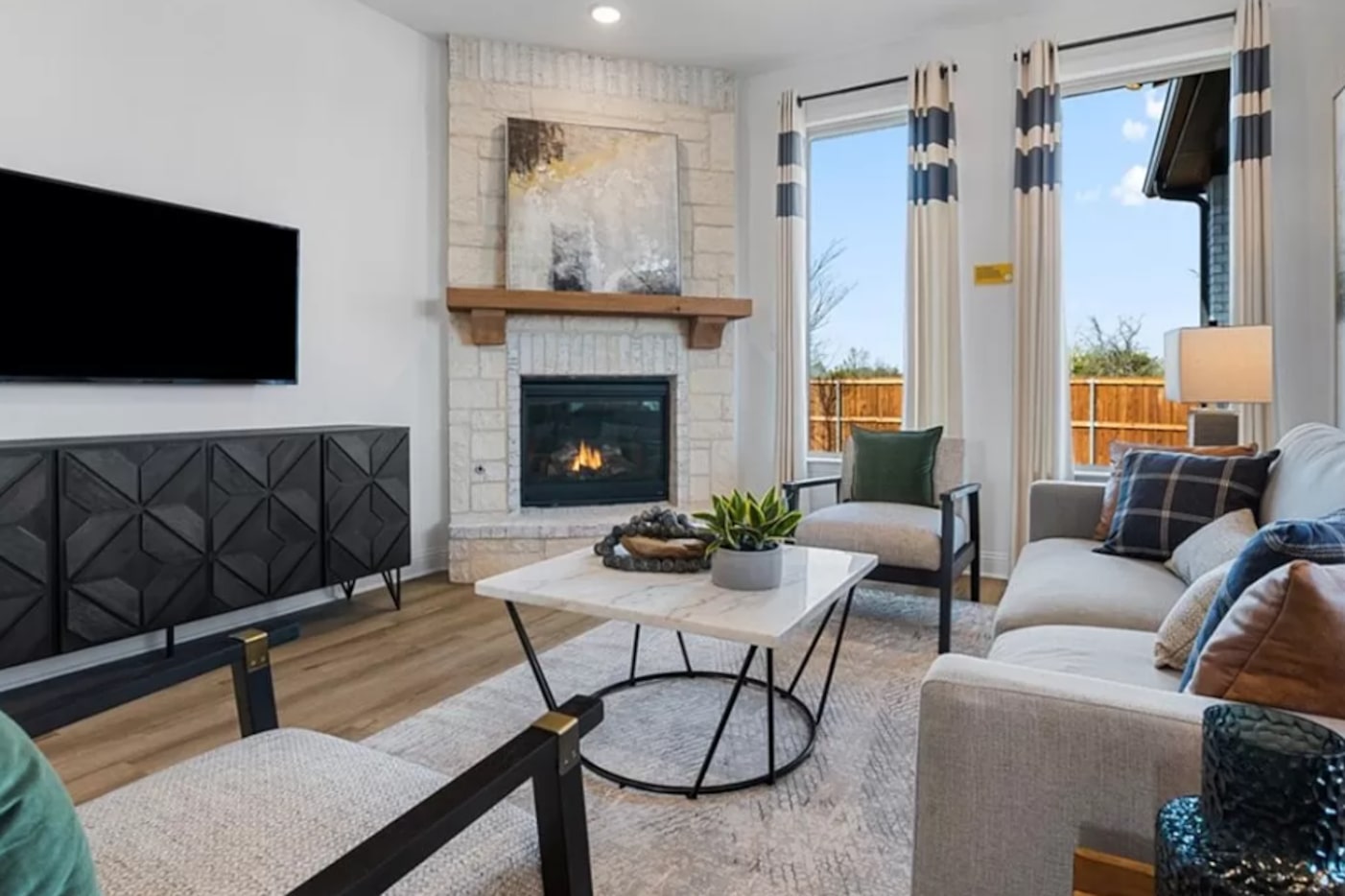 Living room with light vinyl plank floors, neutral furniture and a stone fireplace, plus...