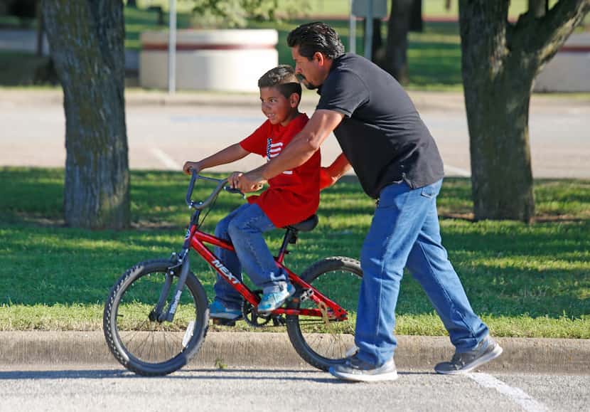 Jose Crispin helps his son, Andrew Garcia, 6, learn to ride his bike at Balch Springs Irwin...