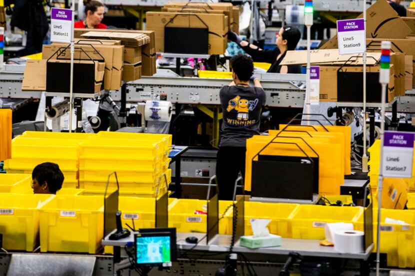 Employees sort packages at an Amazon fulfillment center in Grapevine. (2018 File...