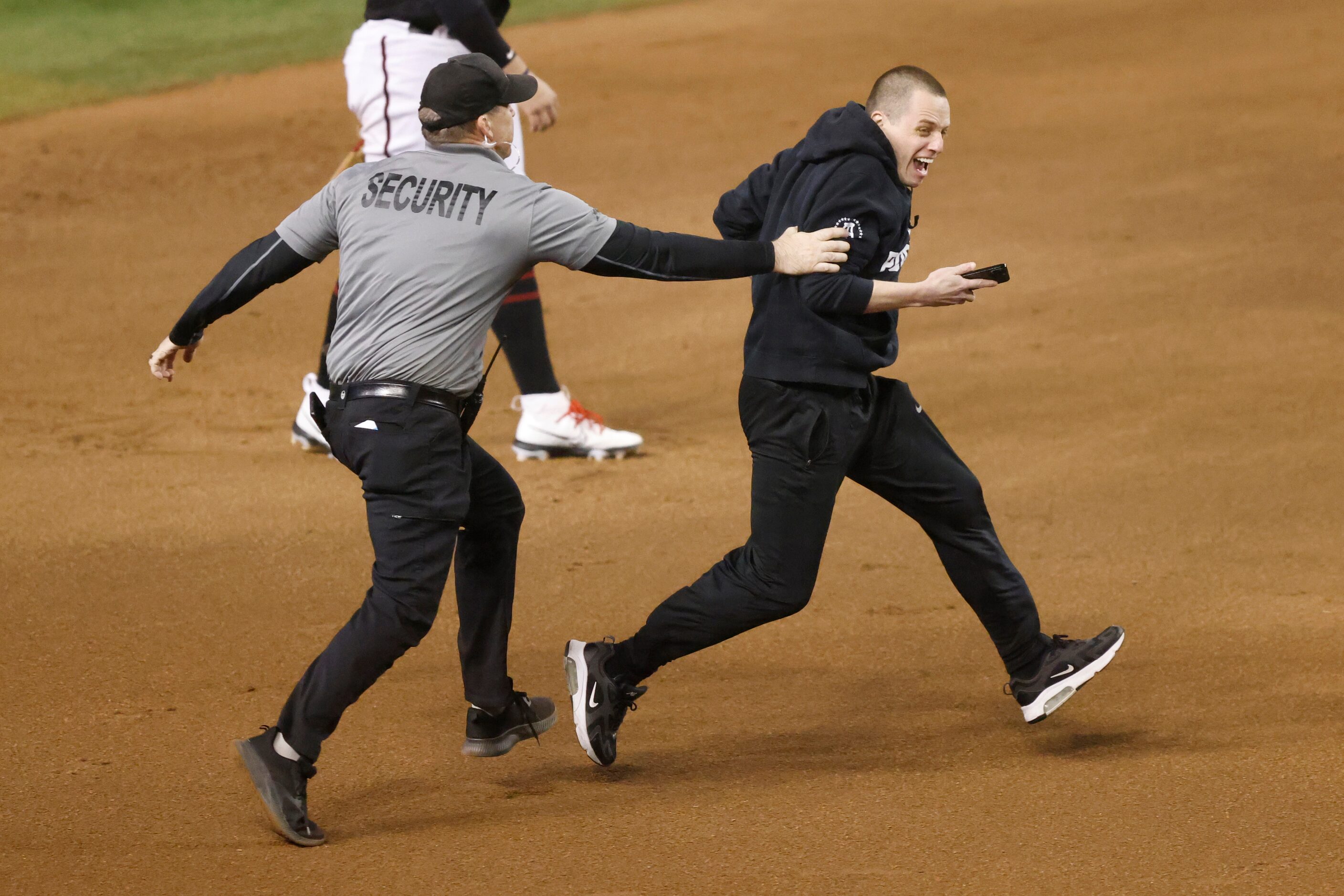 Security chases after a fan who ran onto the field during Game 4 of the World Series between...