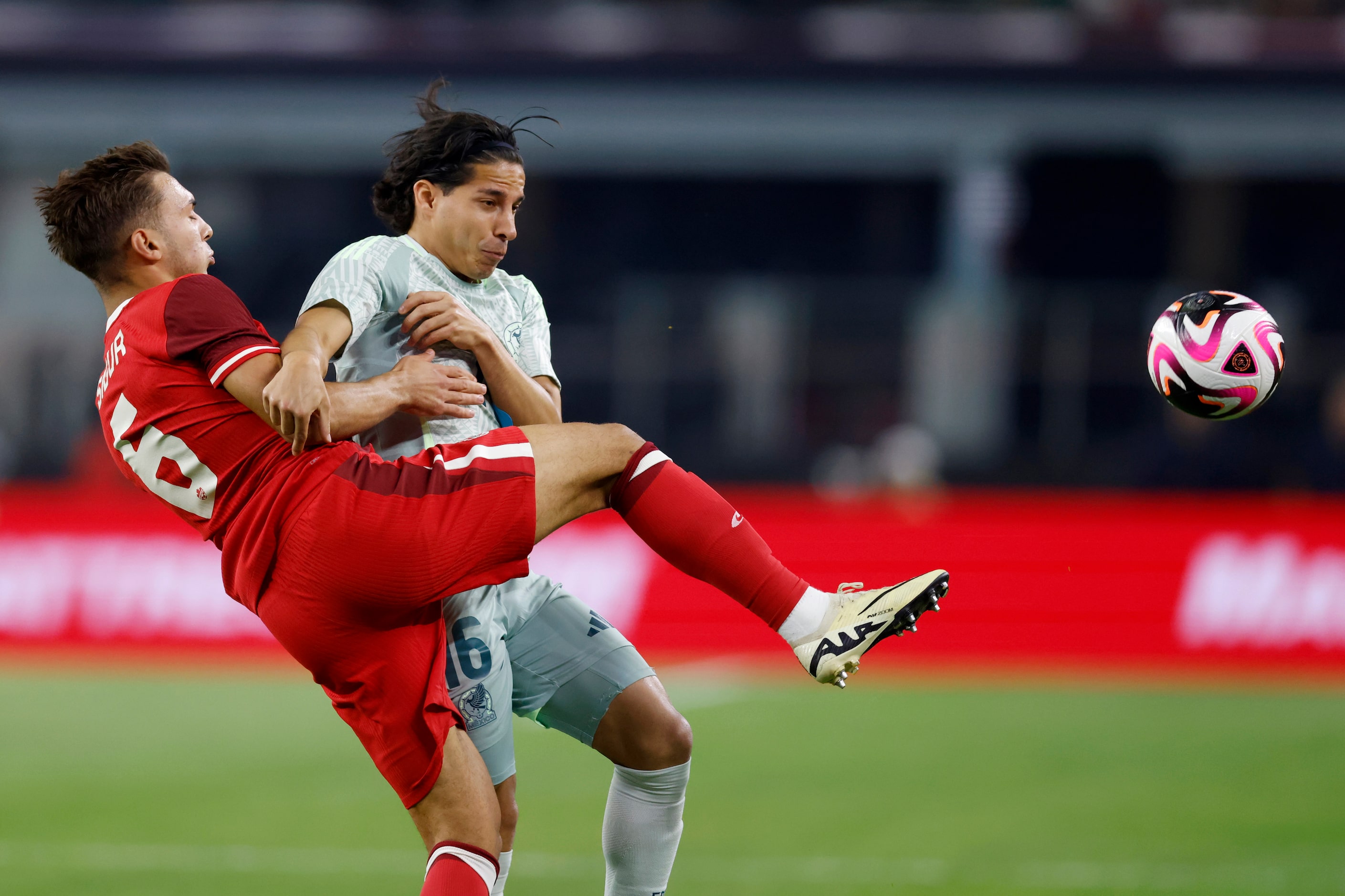 Canada midfielder Niko Sugur (6) kicks the ball away from Mexico midfielder Diego Lainez...