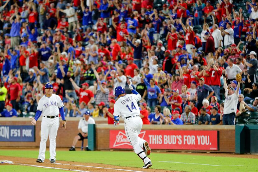 The crowd comes to its feet as Texas Rangers left fielder Carlos Gomez (14) begins to round...
