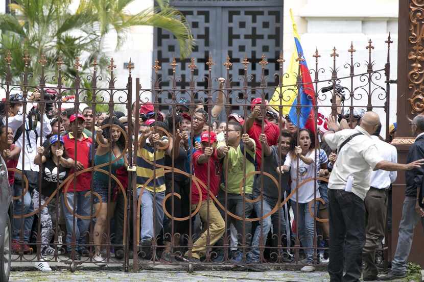 Simpatizantes del presidente Nicolás Maduro derriban la puerta de entrada al patio de la...