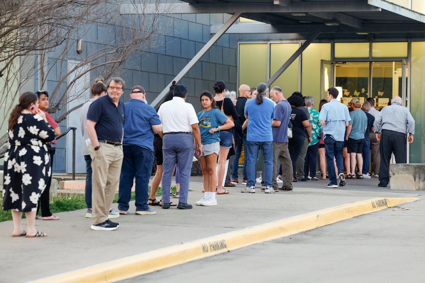 People stand in line outside the Lochwood Branch Library before voting in the state's...