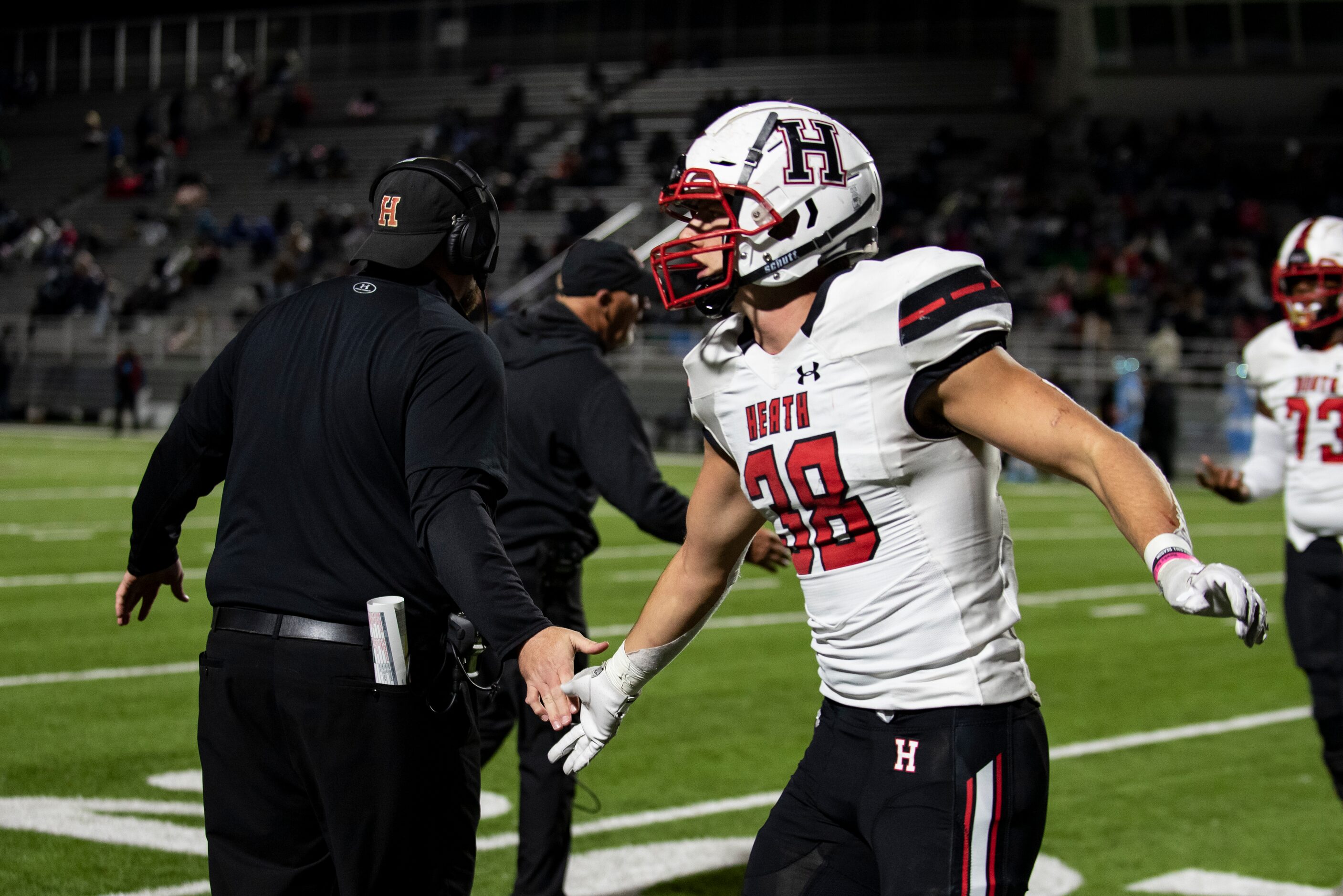 Heath senior Lance Mason (38) high fives a coach after his team scores another touchdown...